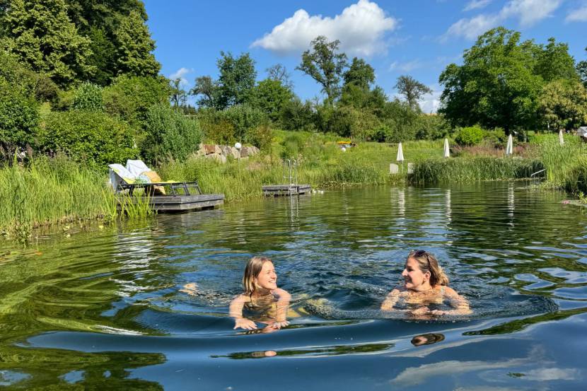 Freundinnen schwimmen im Naturbadeteich