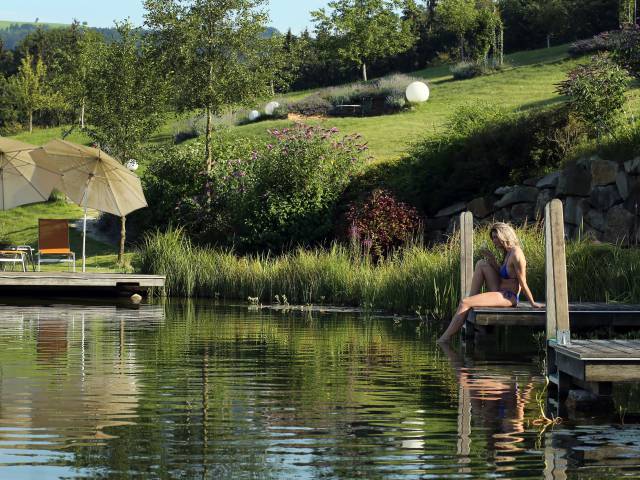 Frau beim Entspannen am Naturbadeteich im RelaxGarten