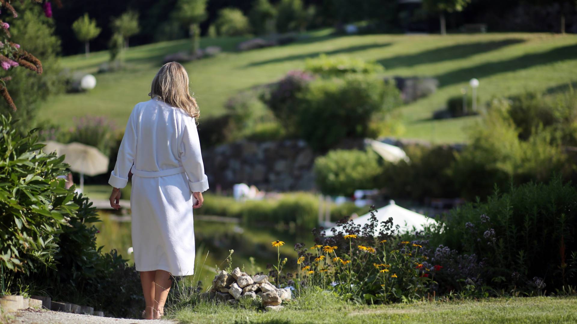 Frau mit Bademantel im Garten vom Wellnesshotel